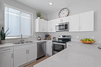 A kitchen with white cabinets and a granite countertop.
